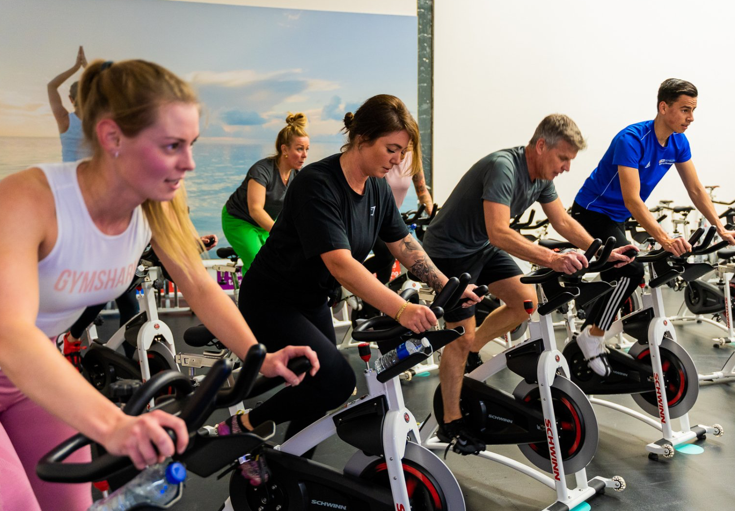 Een groep mensen rijdt op hometrainers in een sportschool.