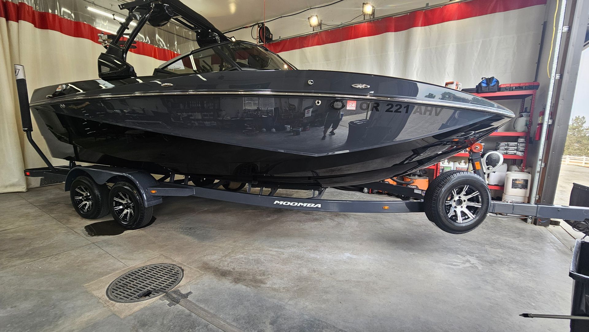 Dark gray boat on a trailer inside a garage with red trim.