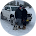 Person kneels near white car in snowy outdoor setting.