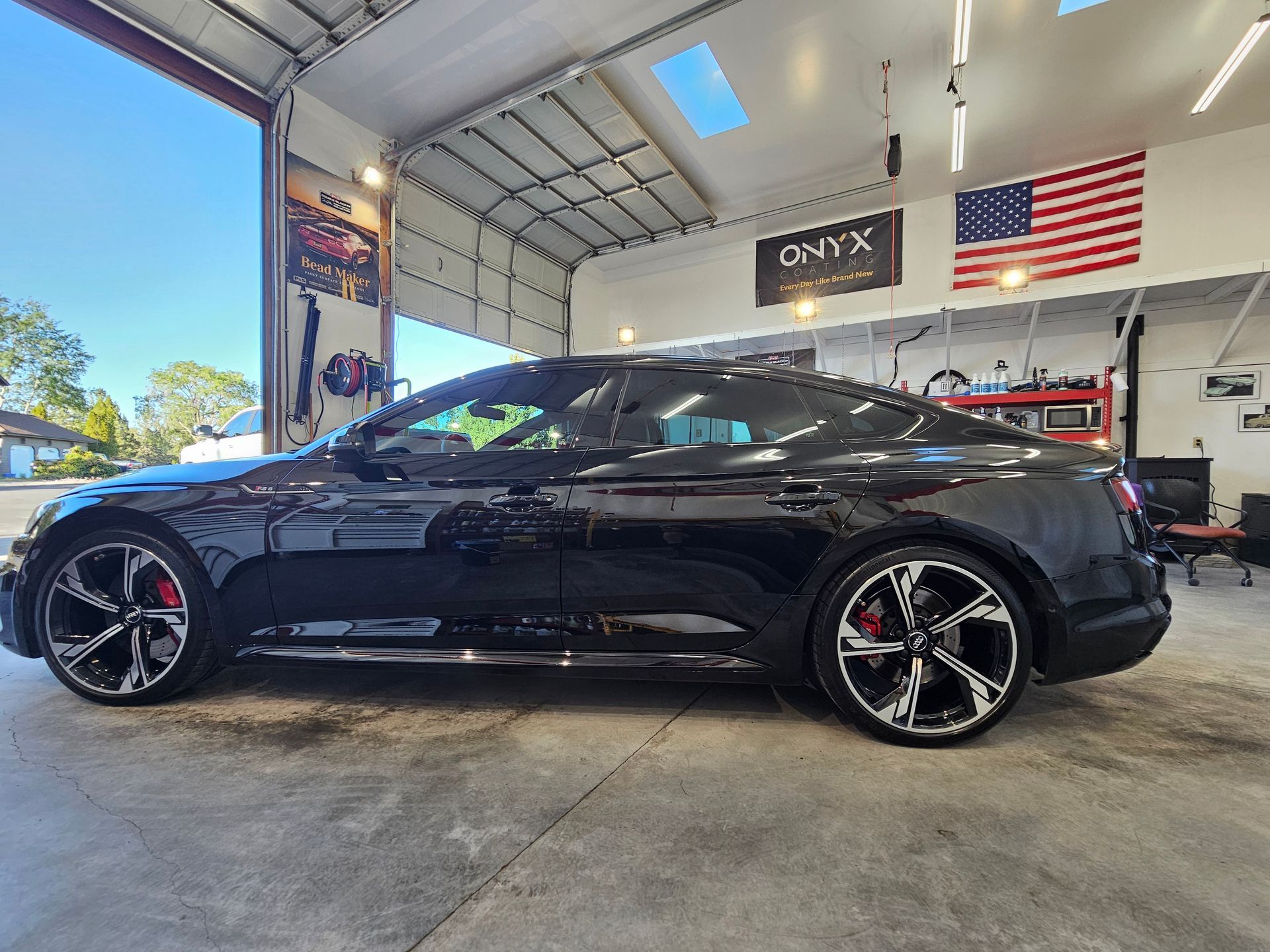 Black sports car inside a garage with an American flag and the word 