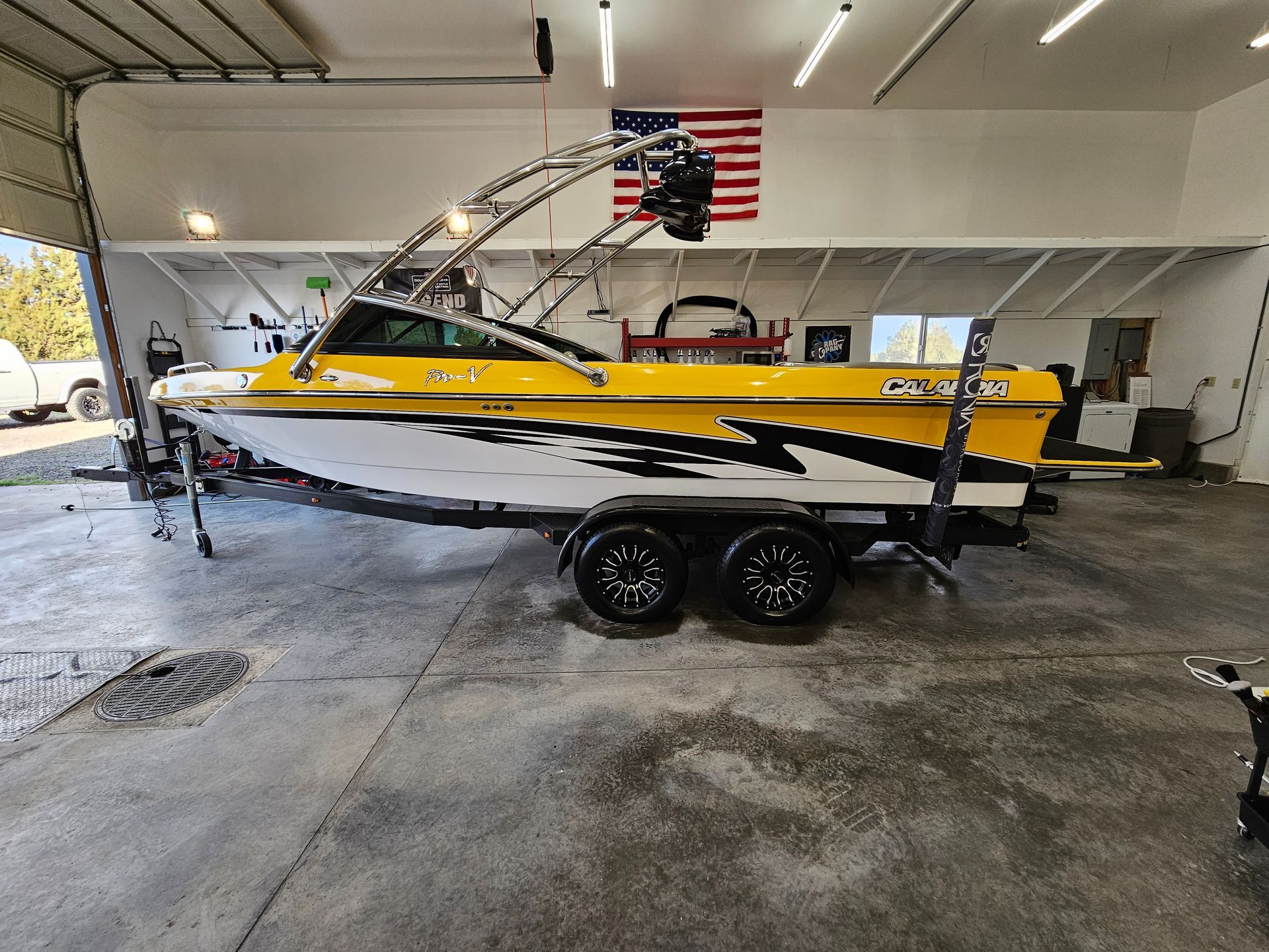 Yellow and black motorboat on a trailer, in a garage with an American flag.