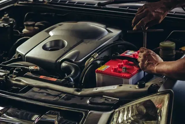 A man is working on the engine of a car with a wrench.