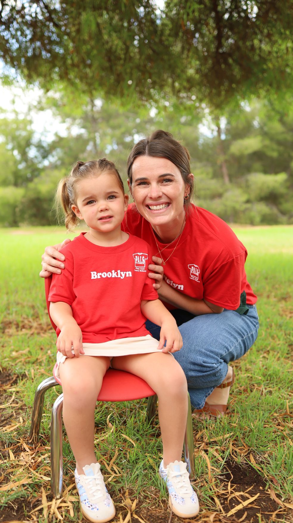 A woman is holding a little boy in her arms in a park.