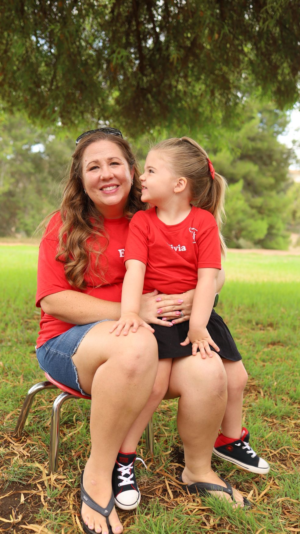 A woman is holding a little girl in her arms in a park.