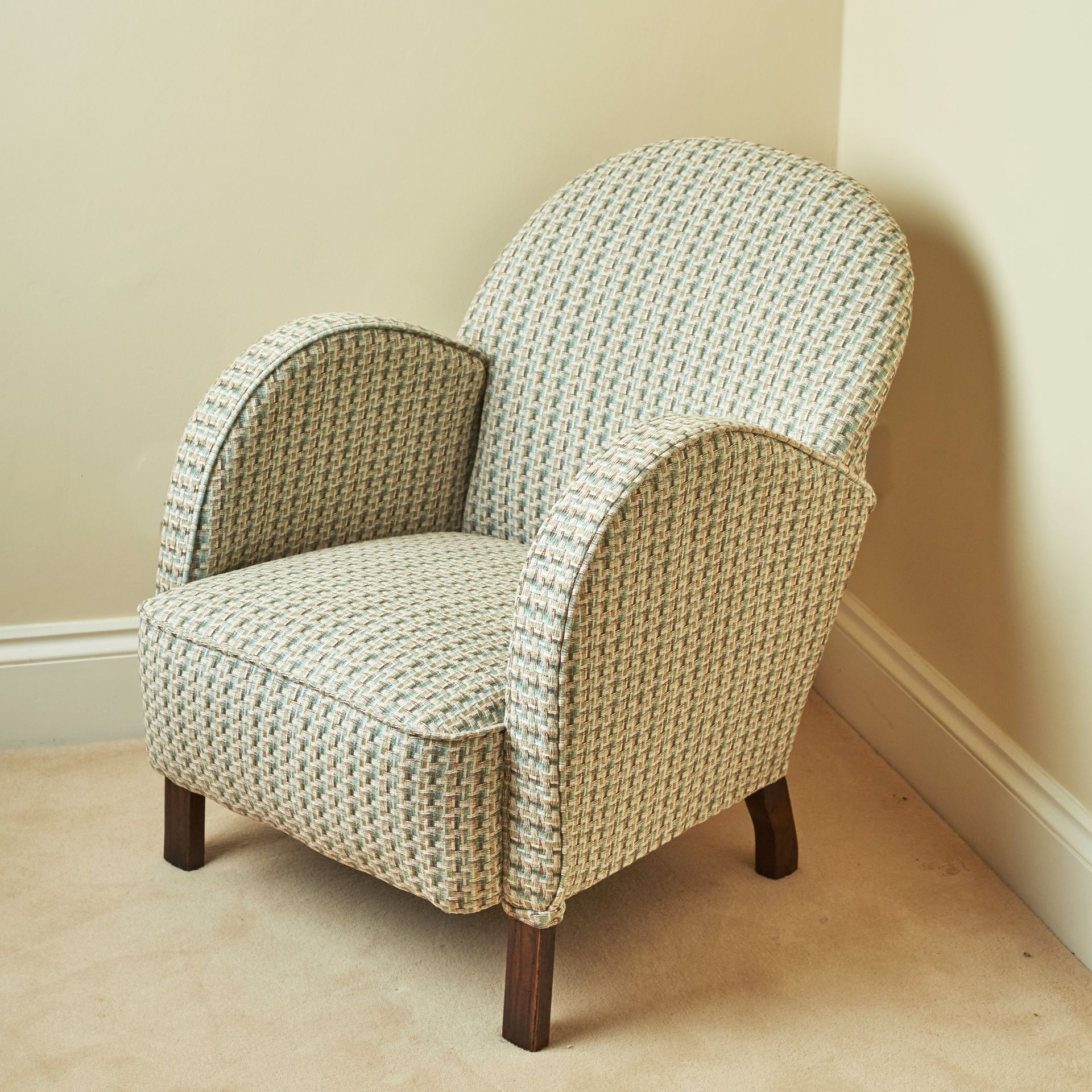 A 1930s chair with bentwood arms and an arched rounded back, upholstered in a stylish multi-coloured basketweave.