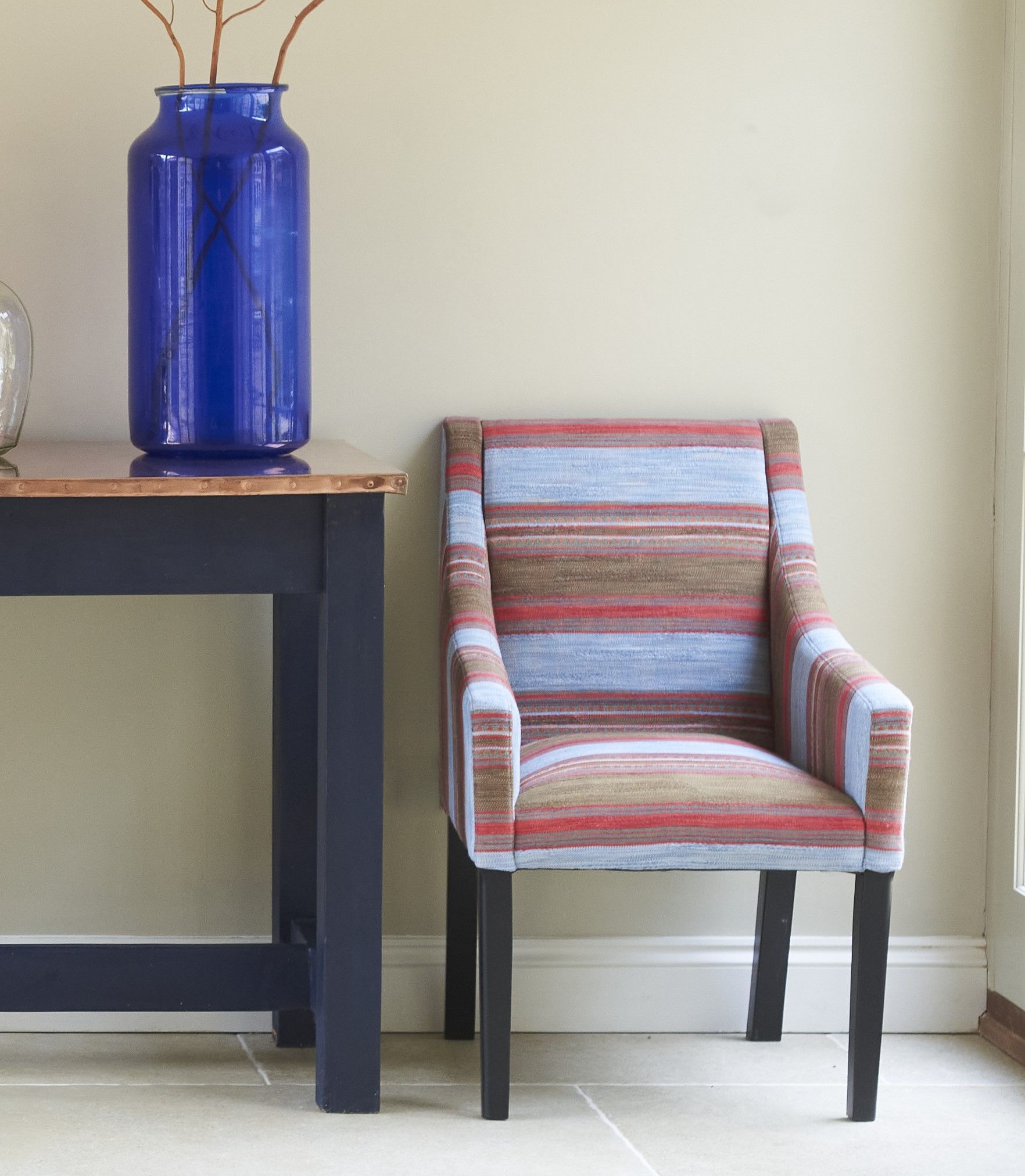 A pair of armchairs with straight legs and back, upholstered in Morroccan style tripes with varying widths and a running triangular motif.