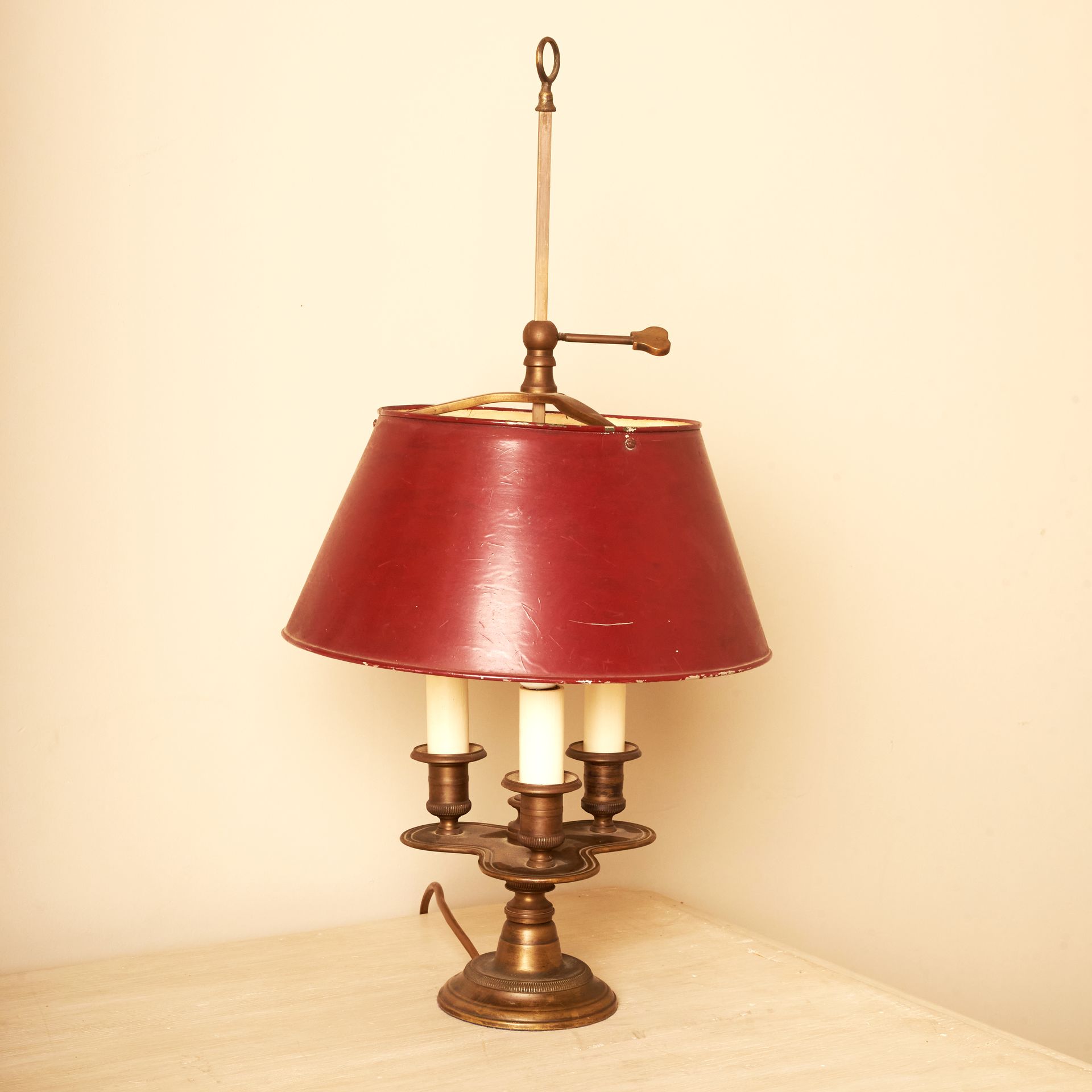French lamp with 3 candles raised on a lilypad-esque pronged construction and a simple red shade.