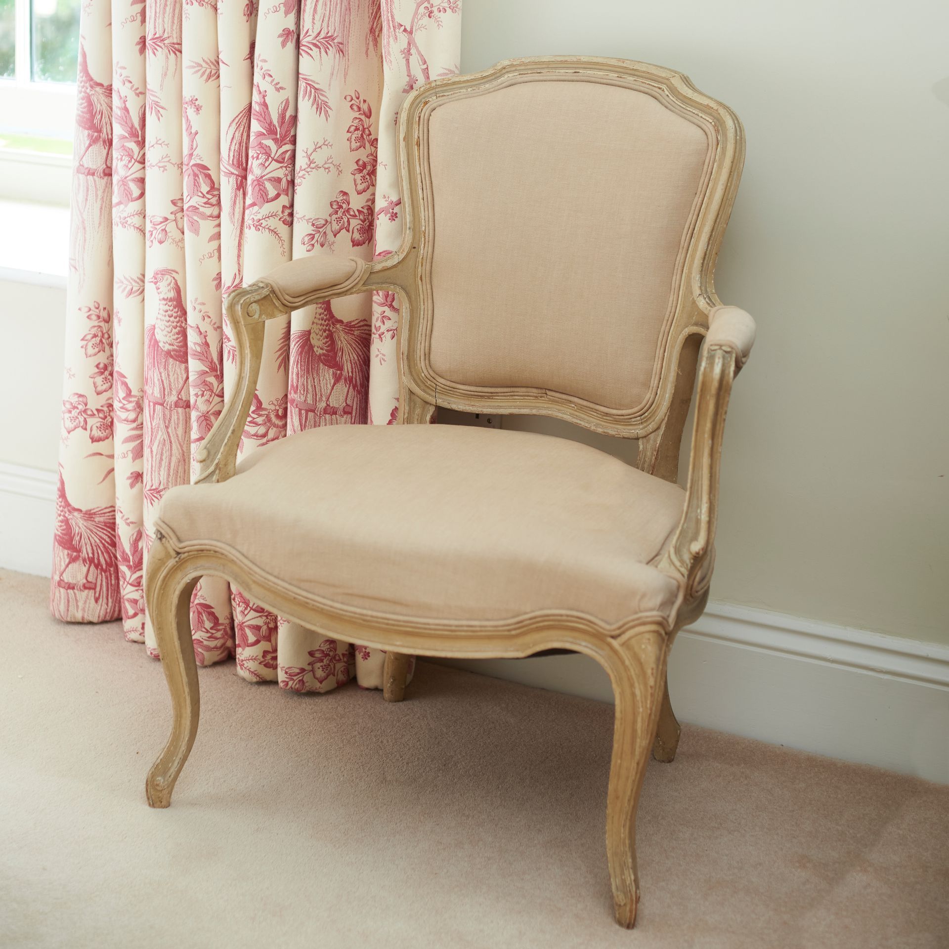 A French antique armchair with elegant woodwork in cream and beige upholstery.