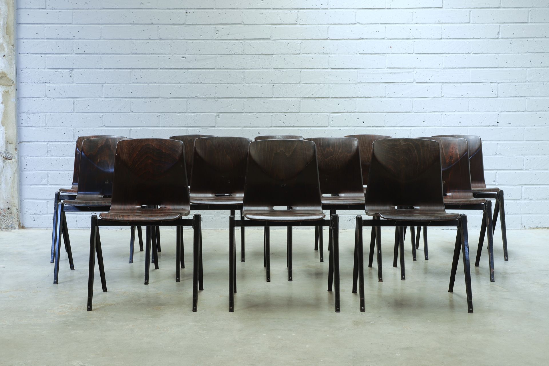 A selection of 12 chairs with laminated walnut seats and stylish black steel frames.