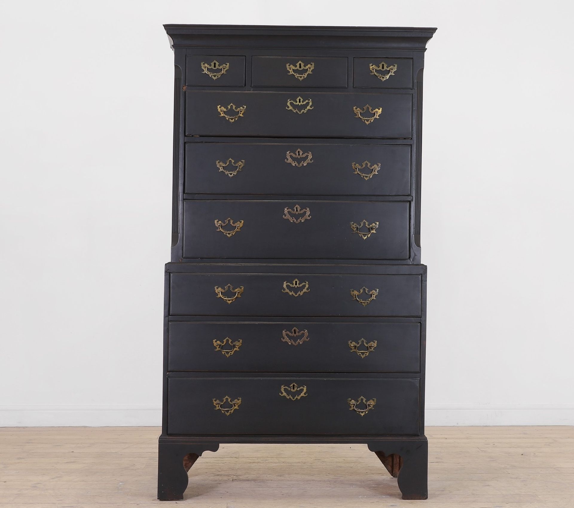 Ebony cabinet with 6 long drawers below 3 smaller drawers with decorative handles.