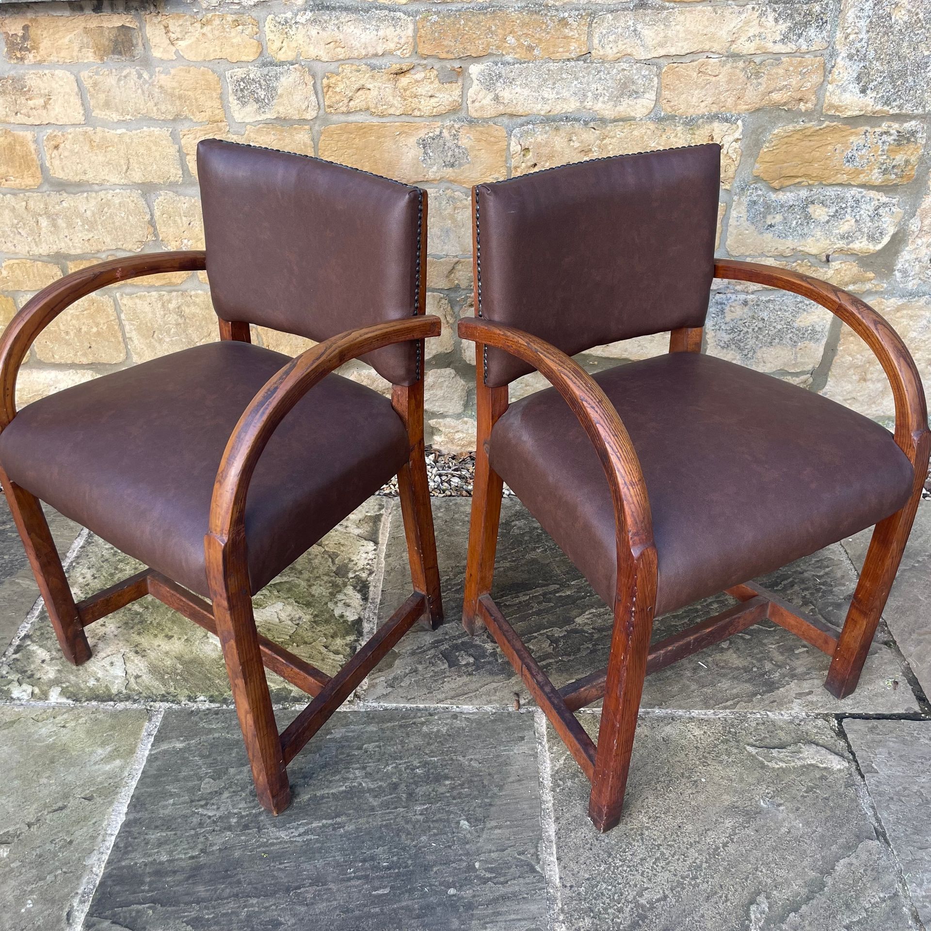2 bentwood armchairs with straight backs, upholstered in a dark red-brown vinyl.