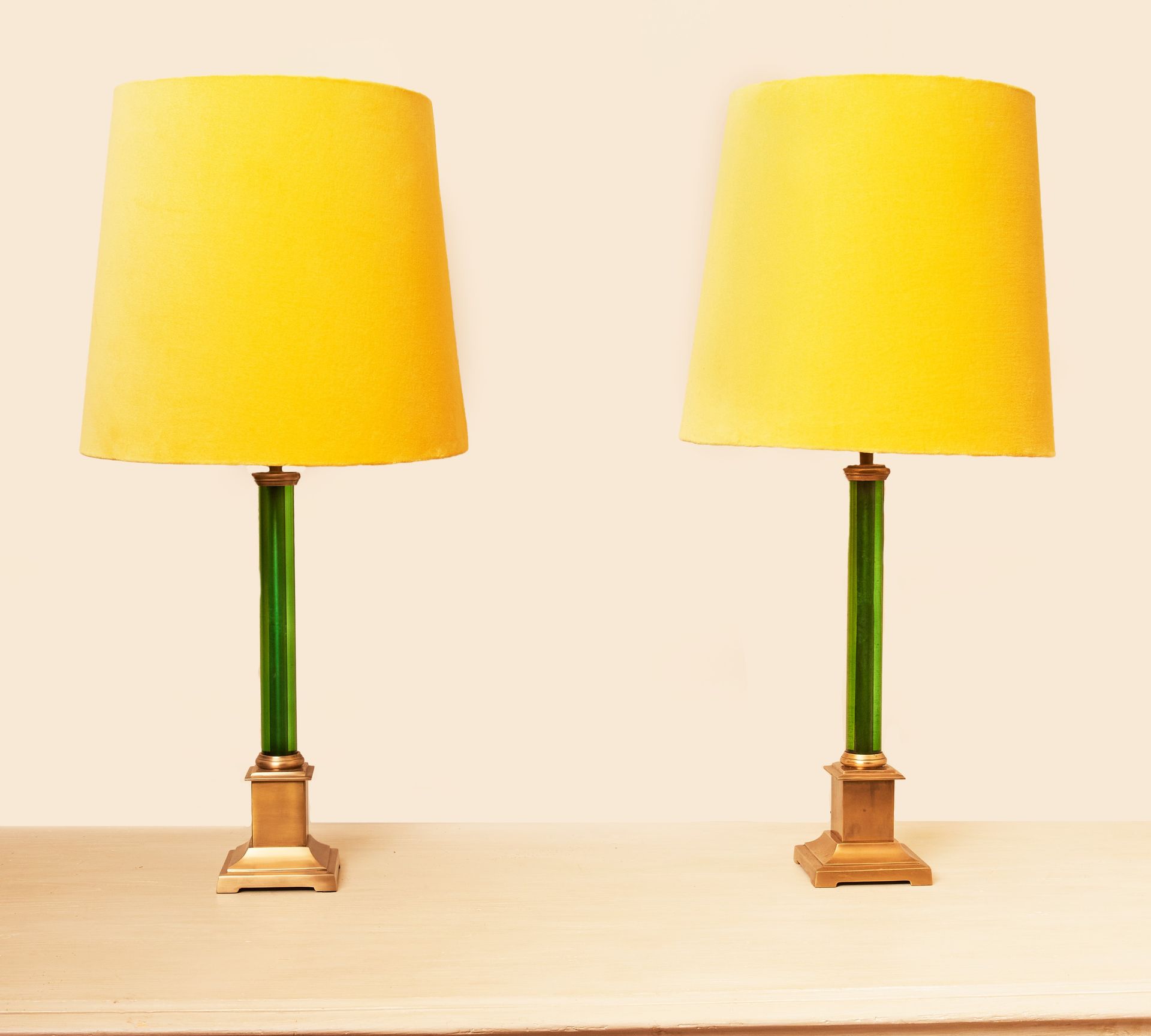 2 lamps with yellow shades and slender green acrylic and brass bases.