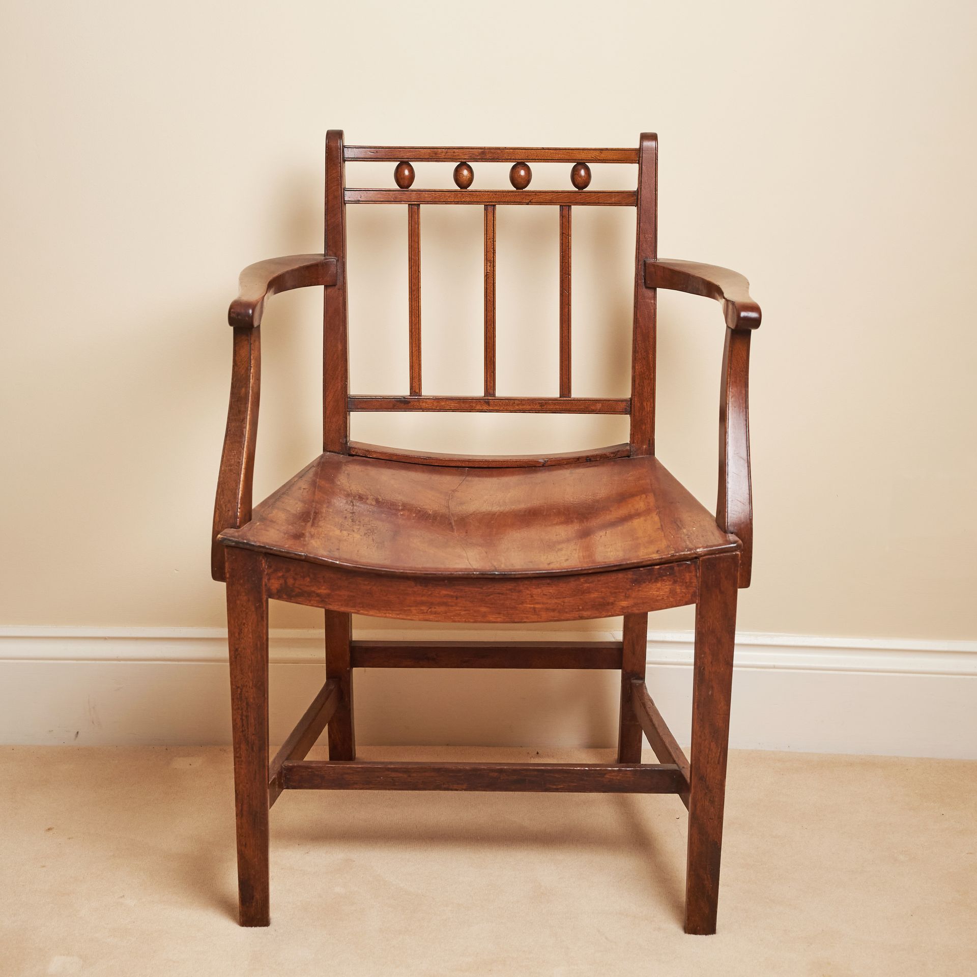 An antique chair from the Regency period with a sloped seat, hipped arms, and a simple square back.
