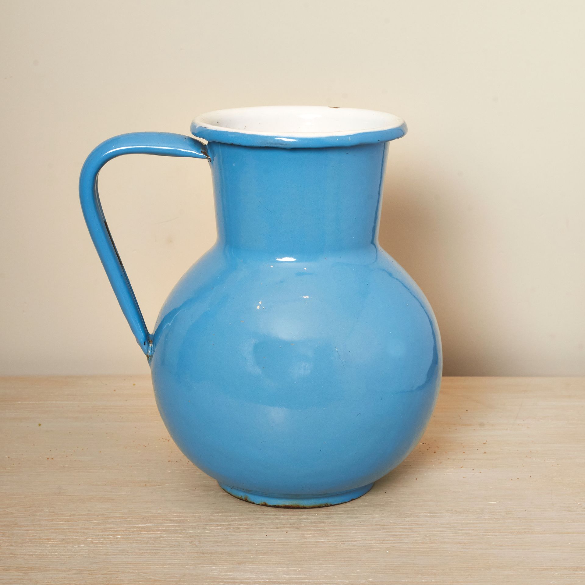 Blue jug with an angular handle, a bulbous base and enamel finish.