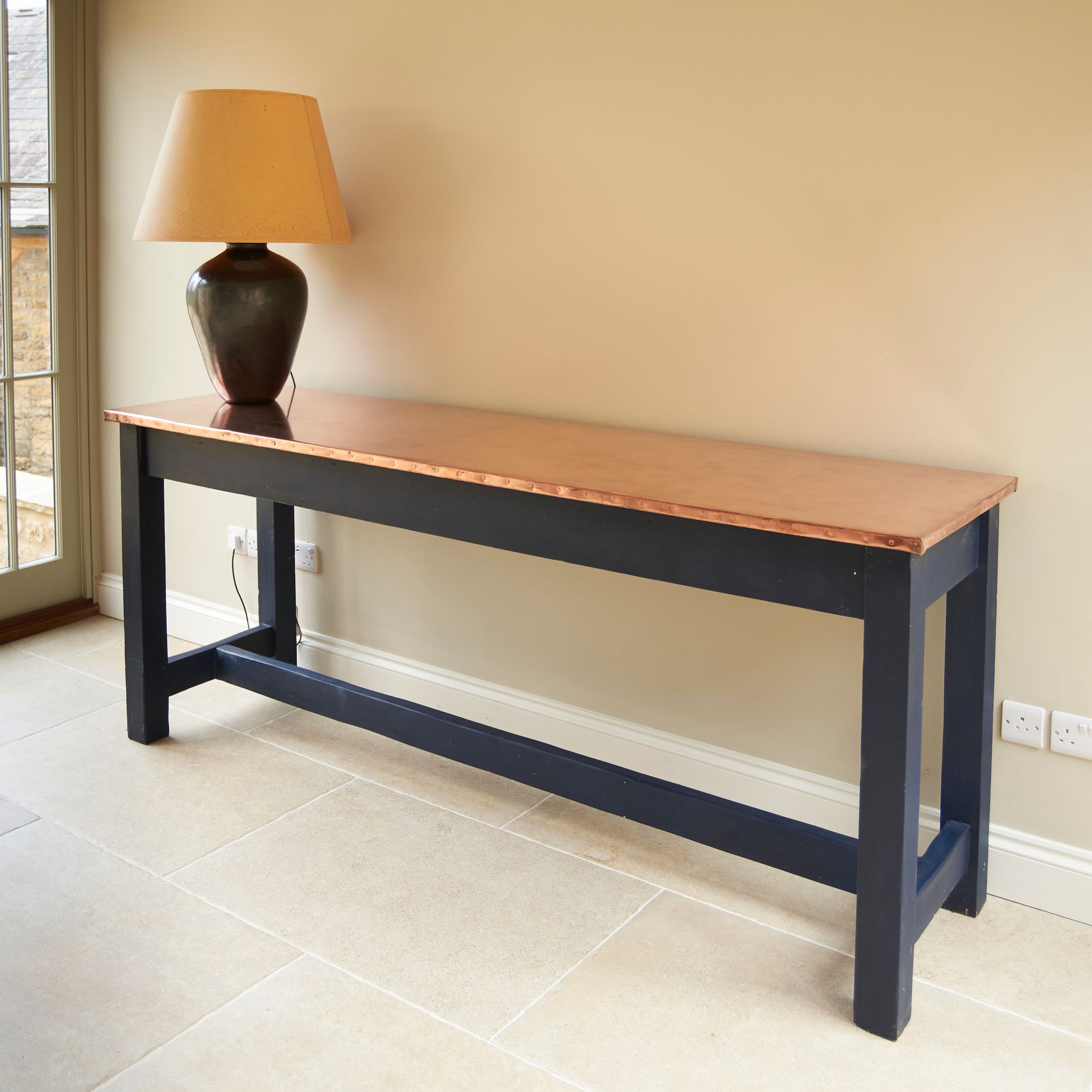 Simple sideboard table with open blue framework and an elegant copper tabletop.