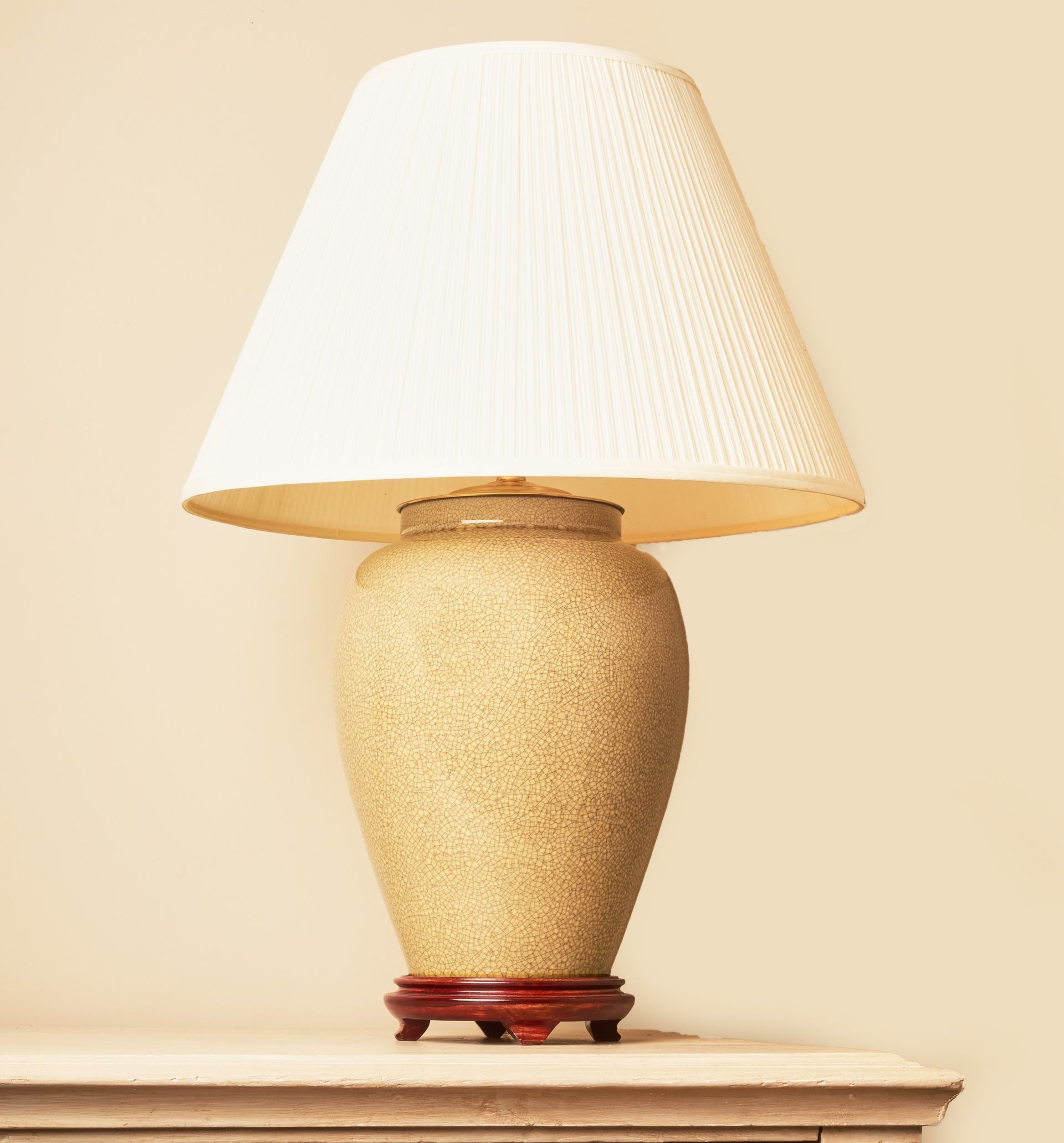 Beige crackle-glaze lamp with a raised wooden base.
