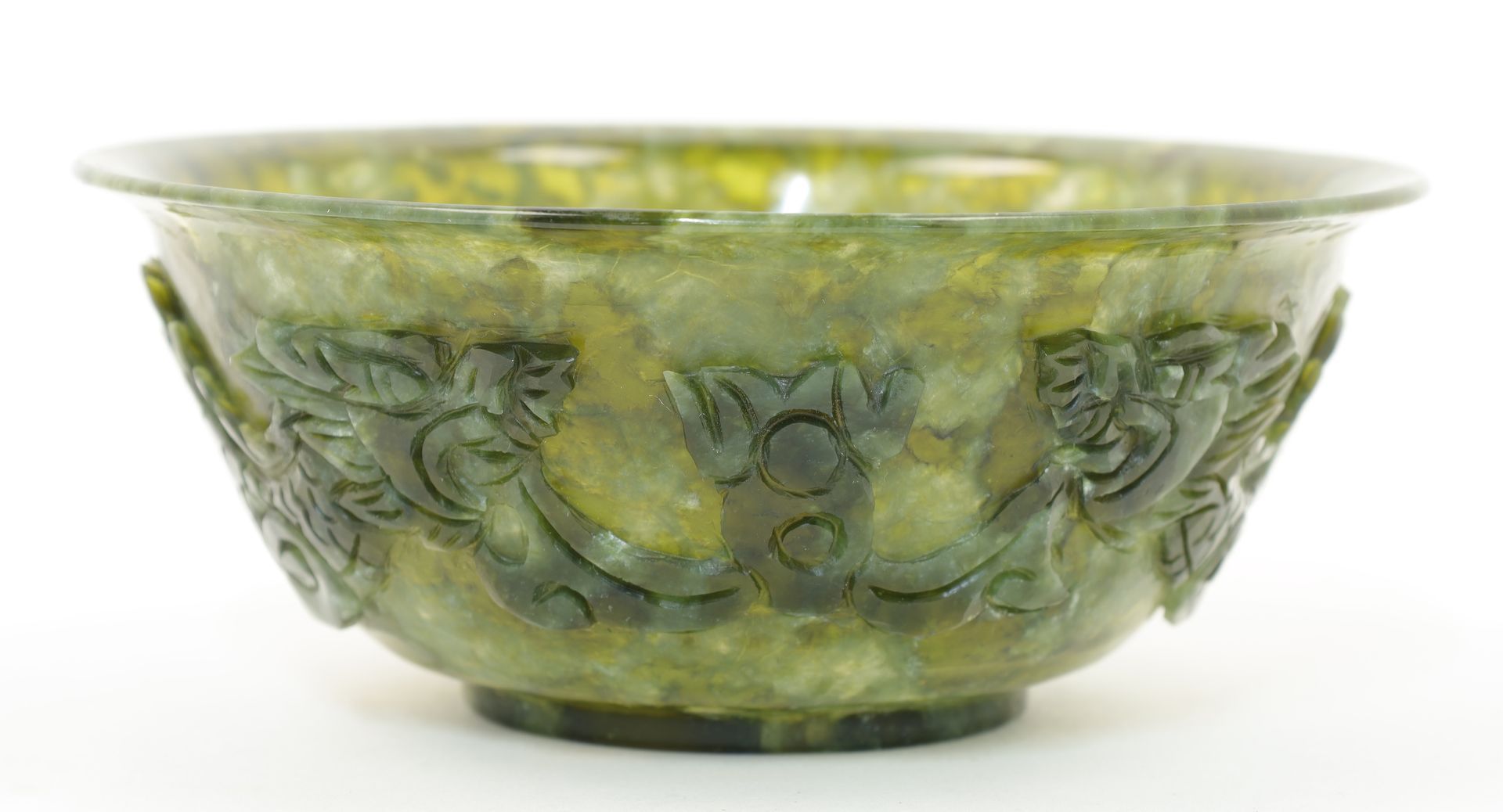Small jade bowl with carved Chinese dragons offset on the outside of the bowl walls. 