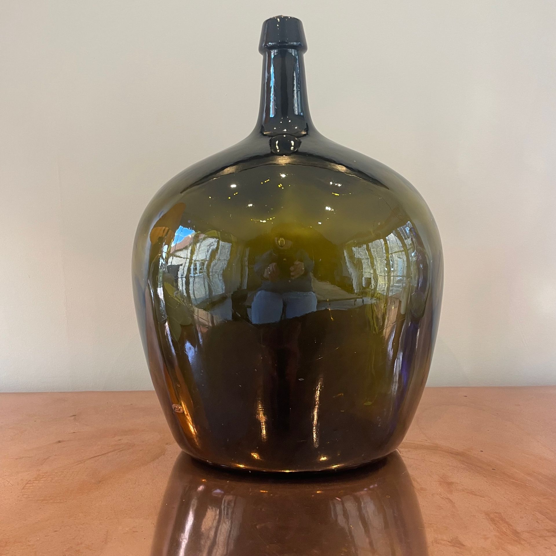 Deep olive green bottle with an ovular body and a slender neck.