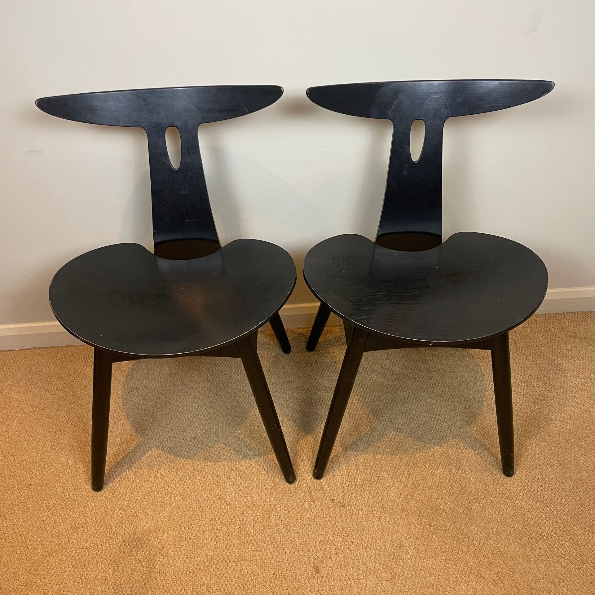 2 wooden chairs in ebony with rounded seats, simple wooden legs, and unique T-shaped backs.