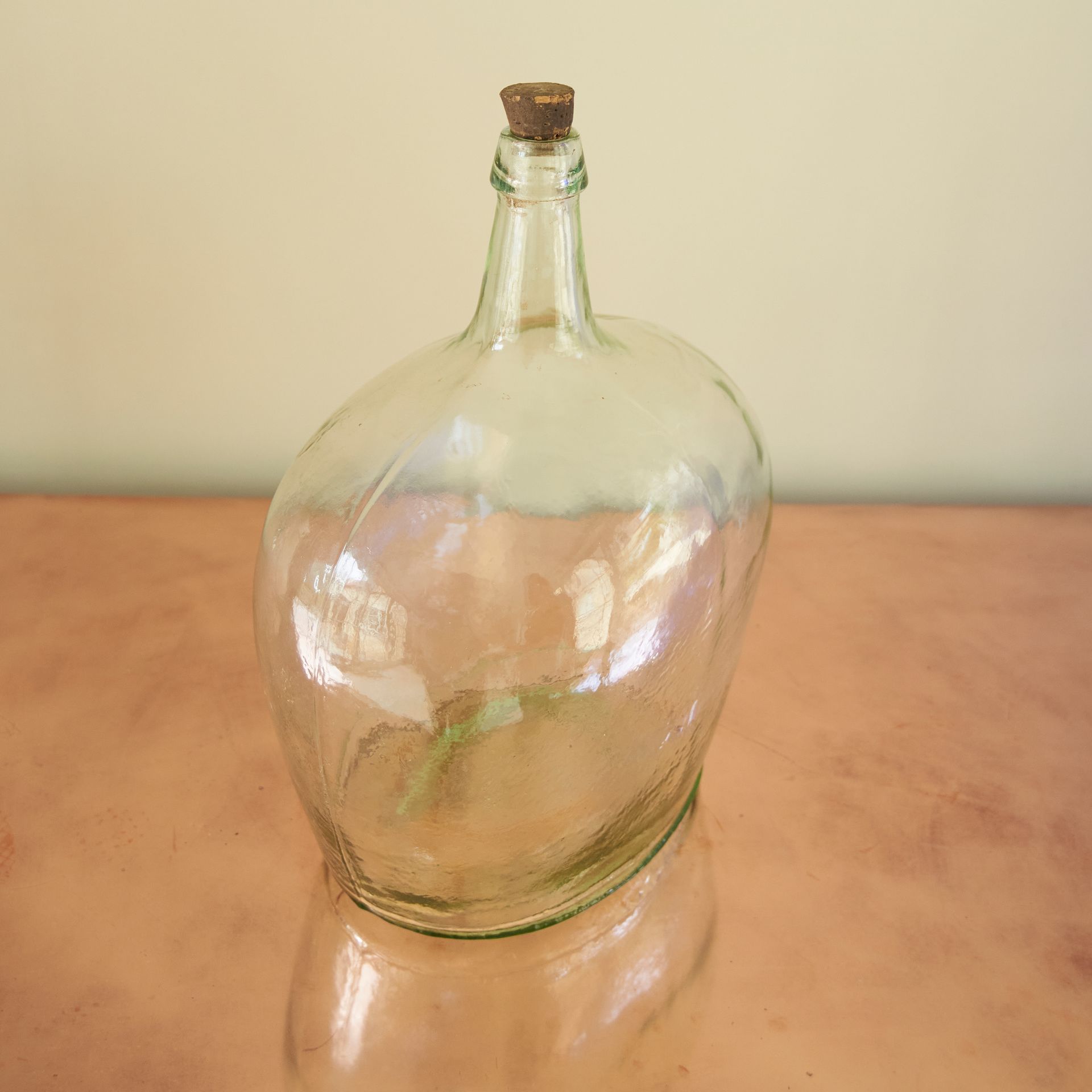 Dramatic oval glass bottle with a slim neck and a cork stopper.