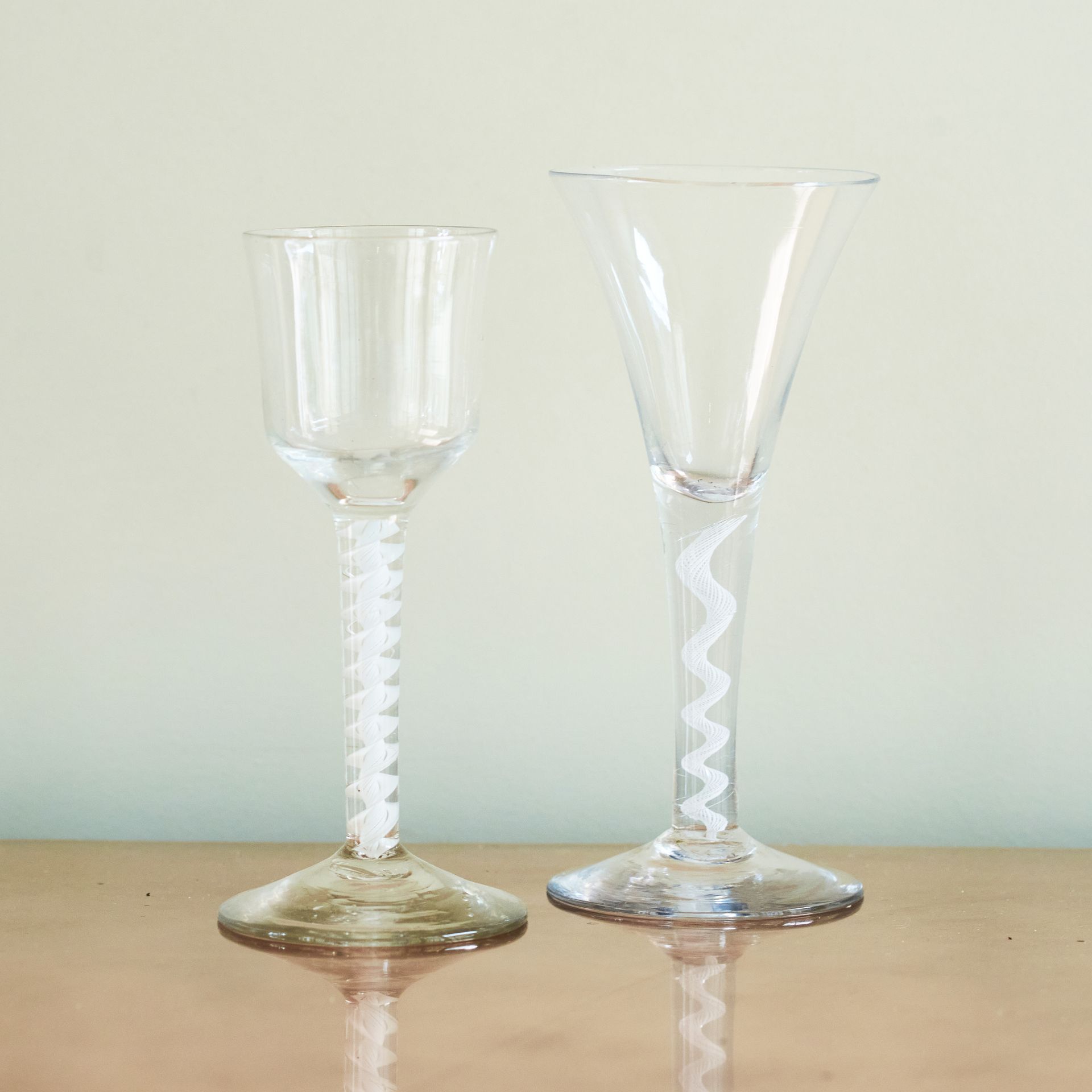 2 glasses with twisting patterns within their glass stems.