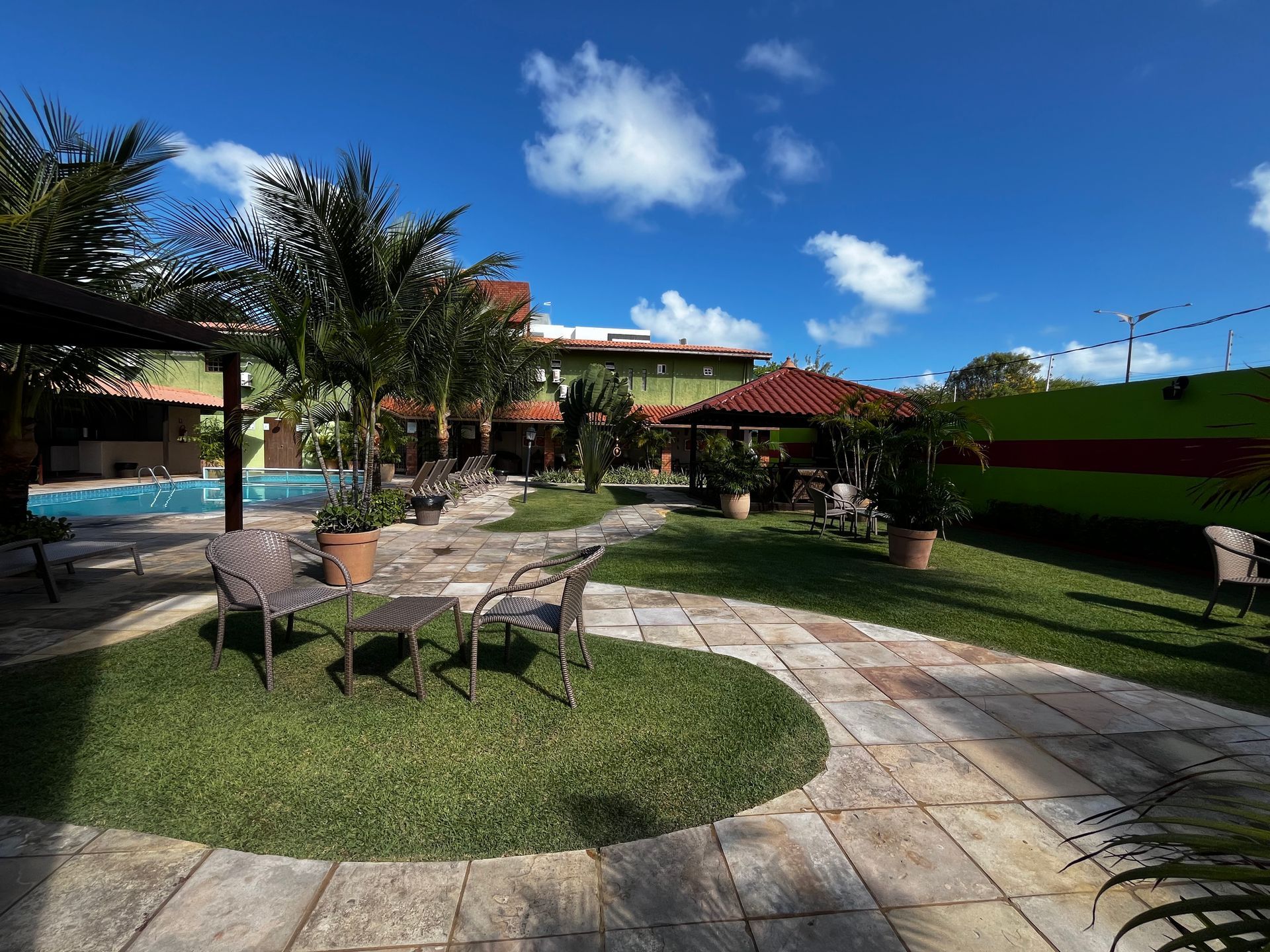 Vista aérea da área da piscina com um pátio revestido de azulejos, grama verde 