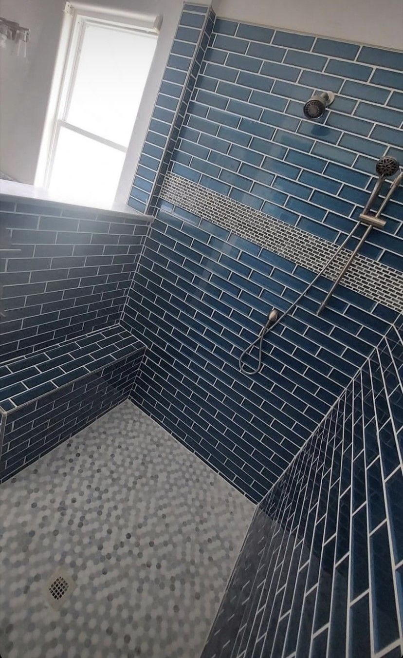Blue tiled shower with a white and gray tile floor. Two shower heads are visible.