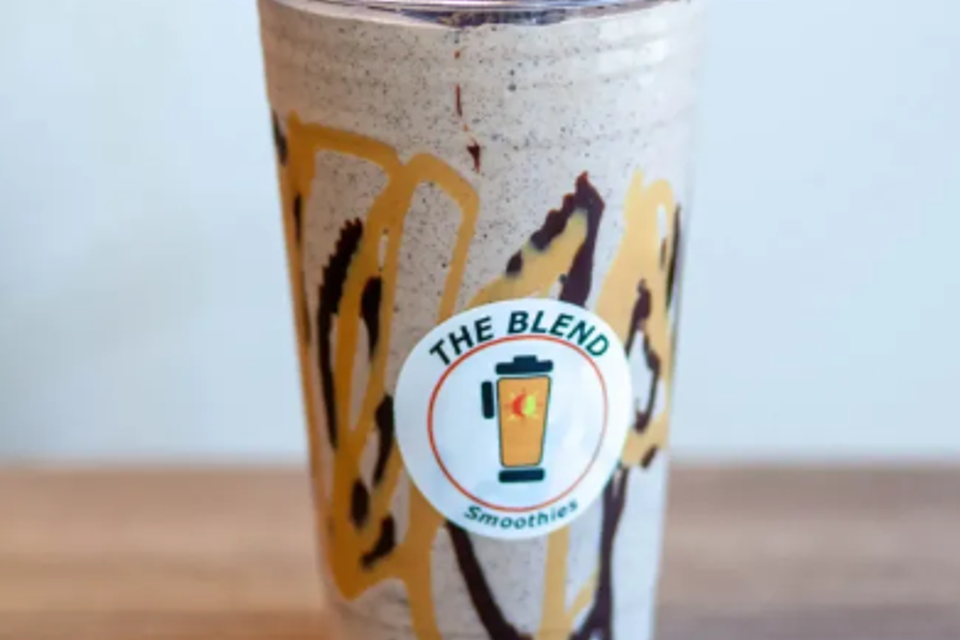 Smoothie with drizzles of caramel and chocolate, in a clear plastic cup with the 