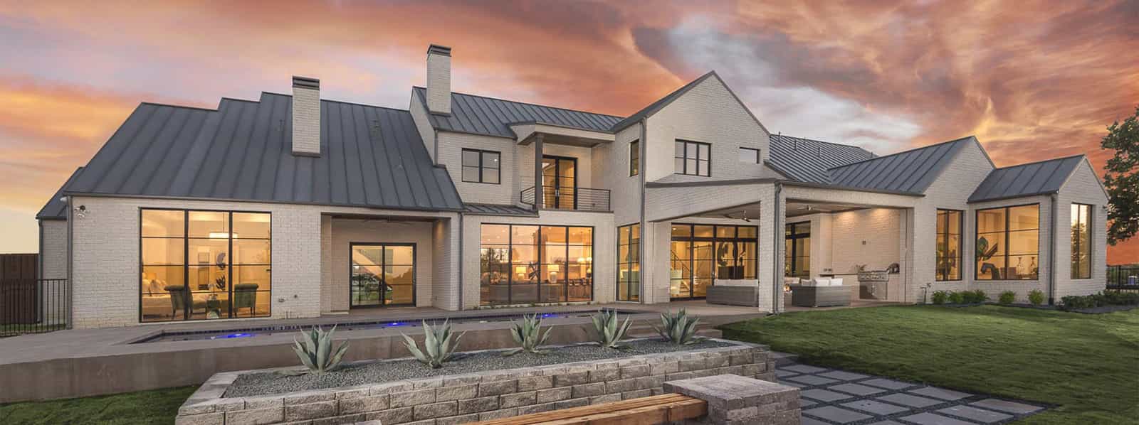 A large white house with a gray roof and a fire pit in front of it.