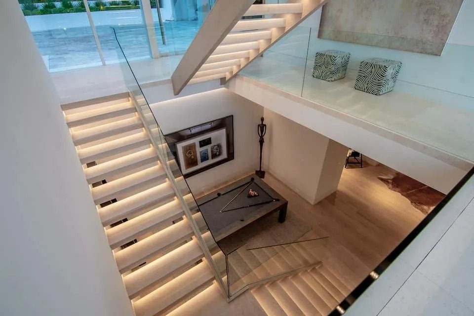 Modern home interior with illuminated stairs and a pool table.