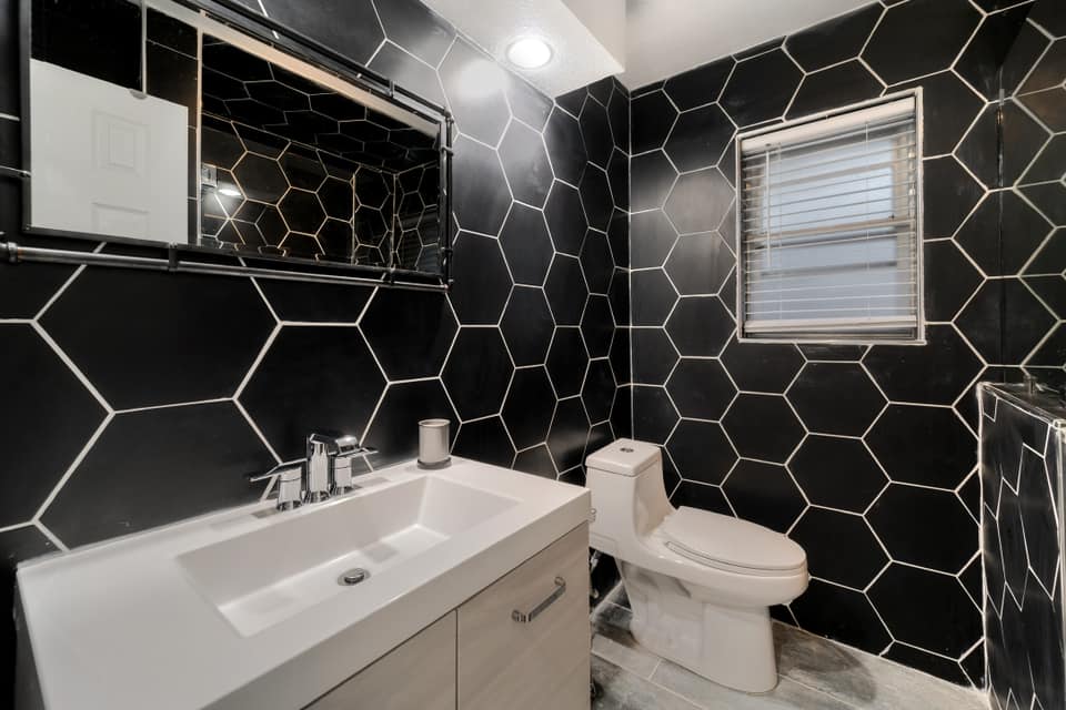 A bathroom with black tiles and a toilet and sink