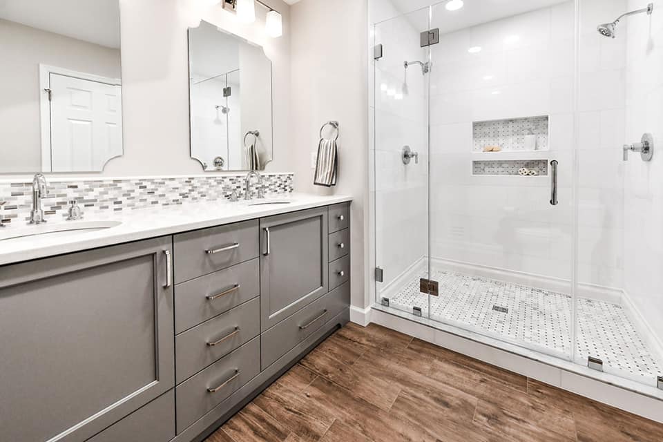A bathroom with a walk in shower , sink and mirror.