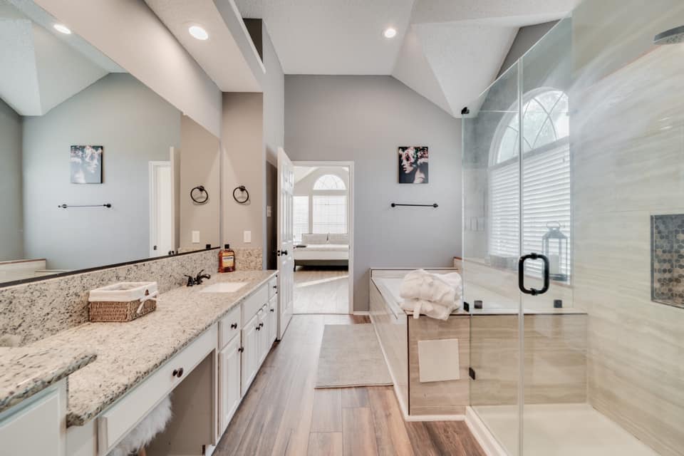 A bathroom with two sinks , a tub , and a walk in shower.