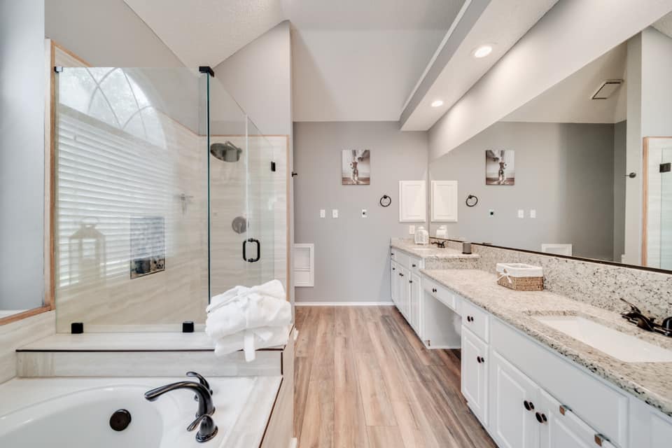 A bathroom with two sinks , a tub , and a walk in shower.