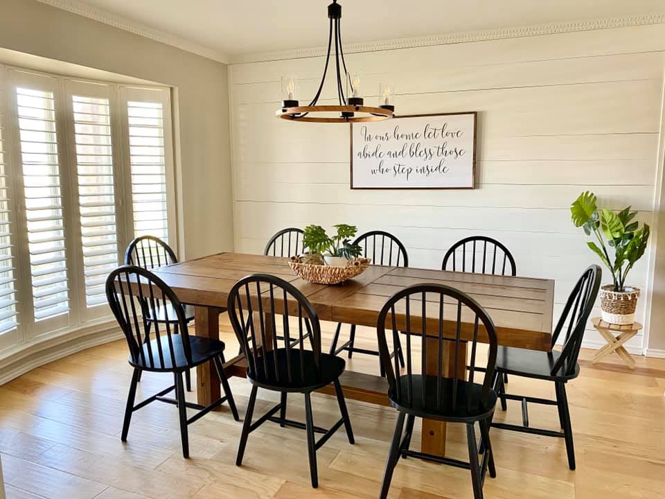A dining room with a wooden table and black chairs.