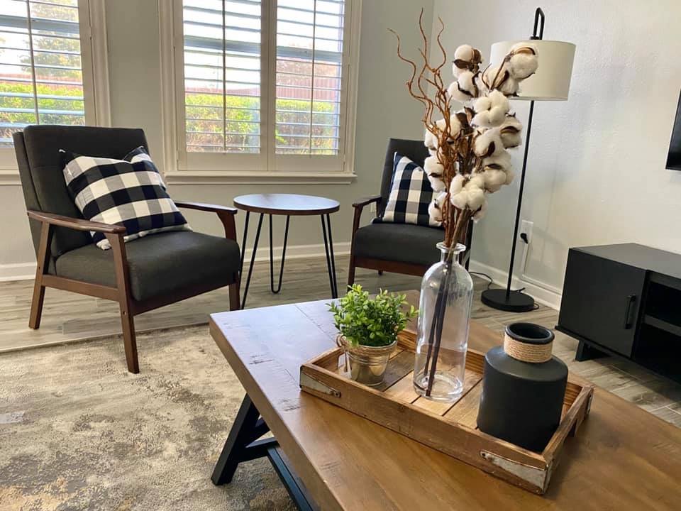A living room with two chairs , a coffee table , and a lamp.