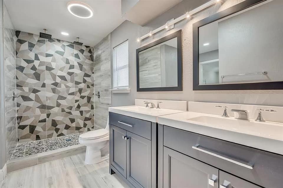A bathroom with two sinks , a toilet , and a walk in shower.