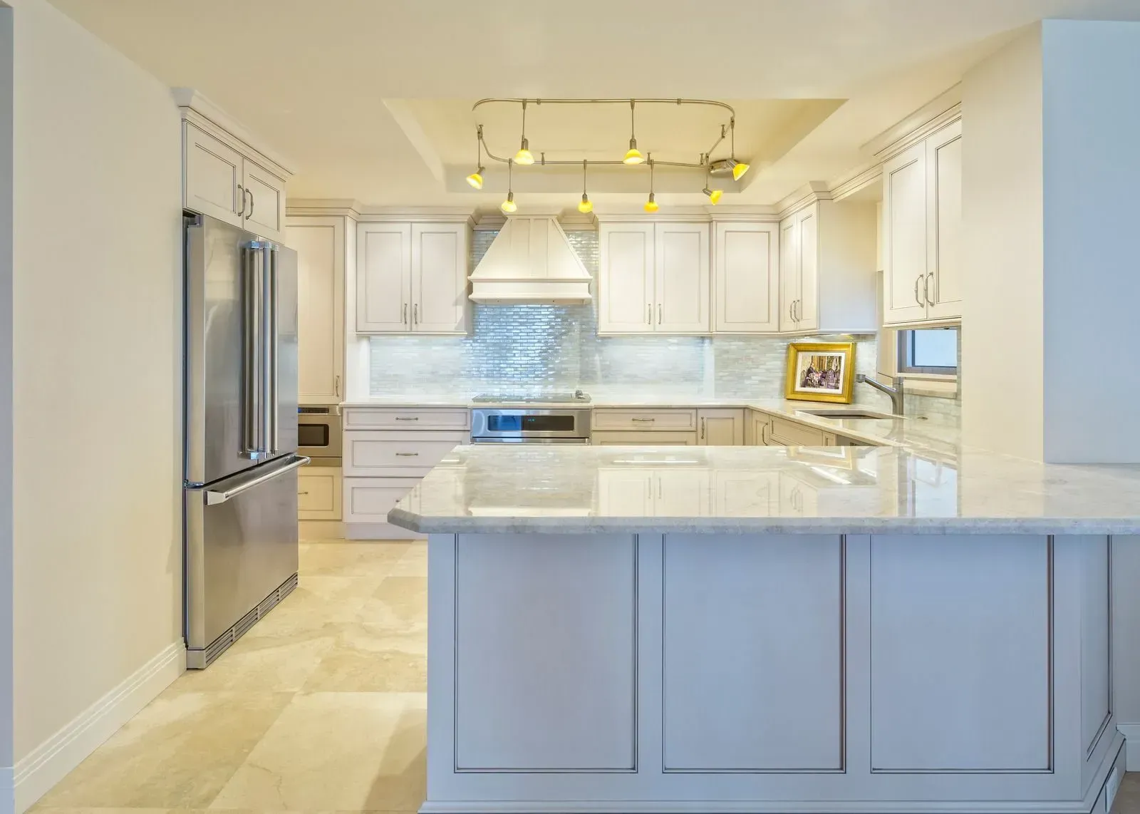 White kitchen with stainless steel appliances, marble countertops, and island.