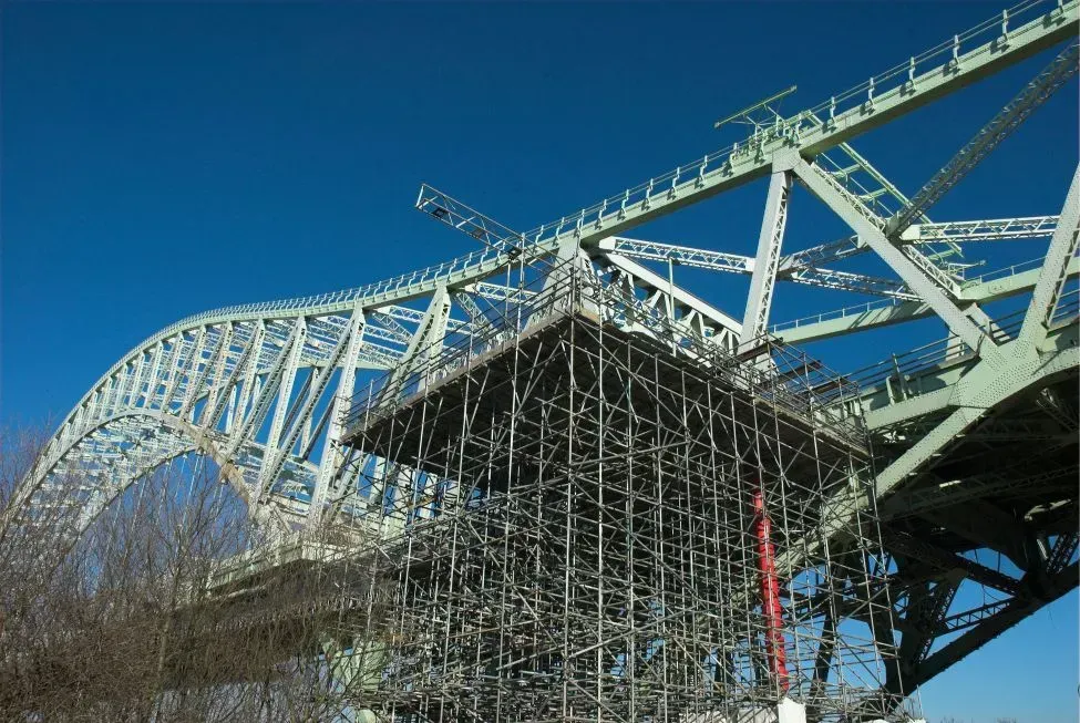 Scaffolding and bridge arch against a bright blue sky.