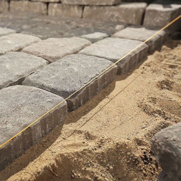 A man is laying bricks on a wall with a trowel.
