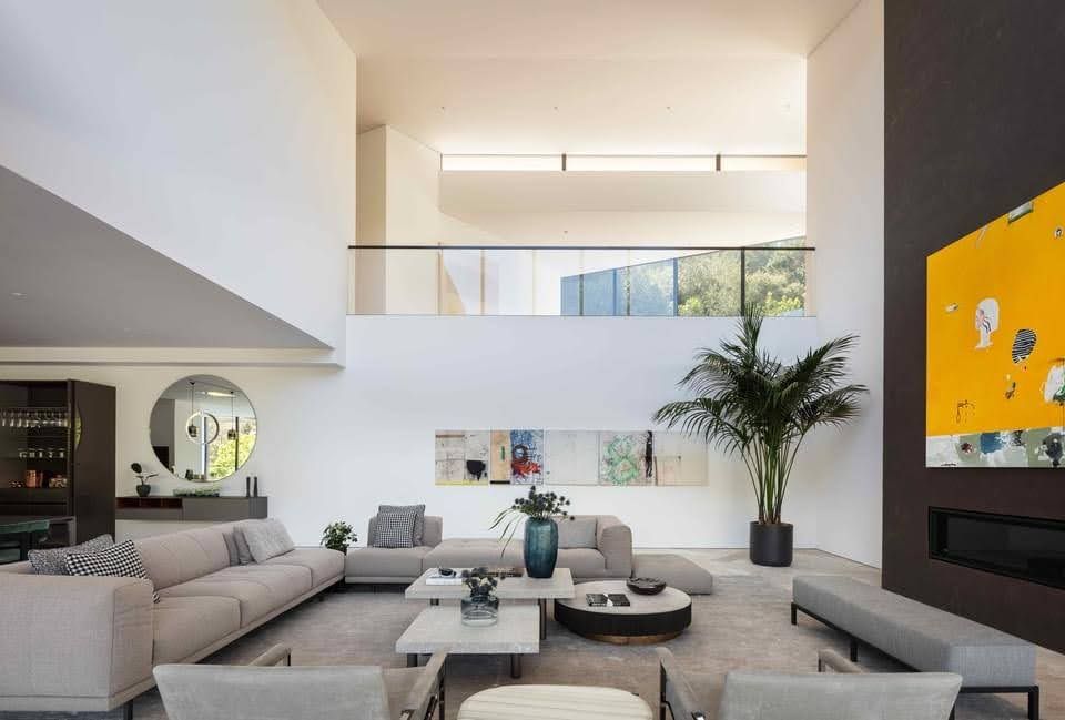 Modern living room with high ceilings, white walls, and neutral furniture.