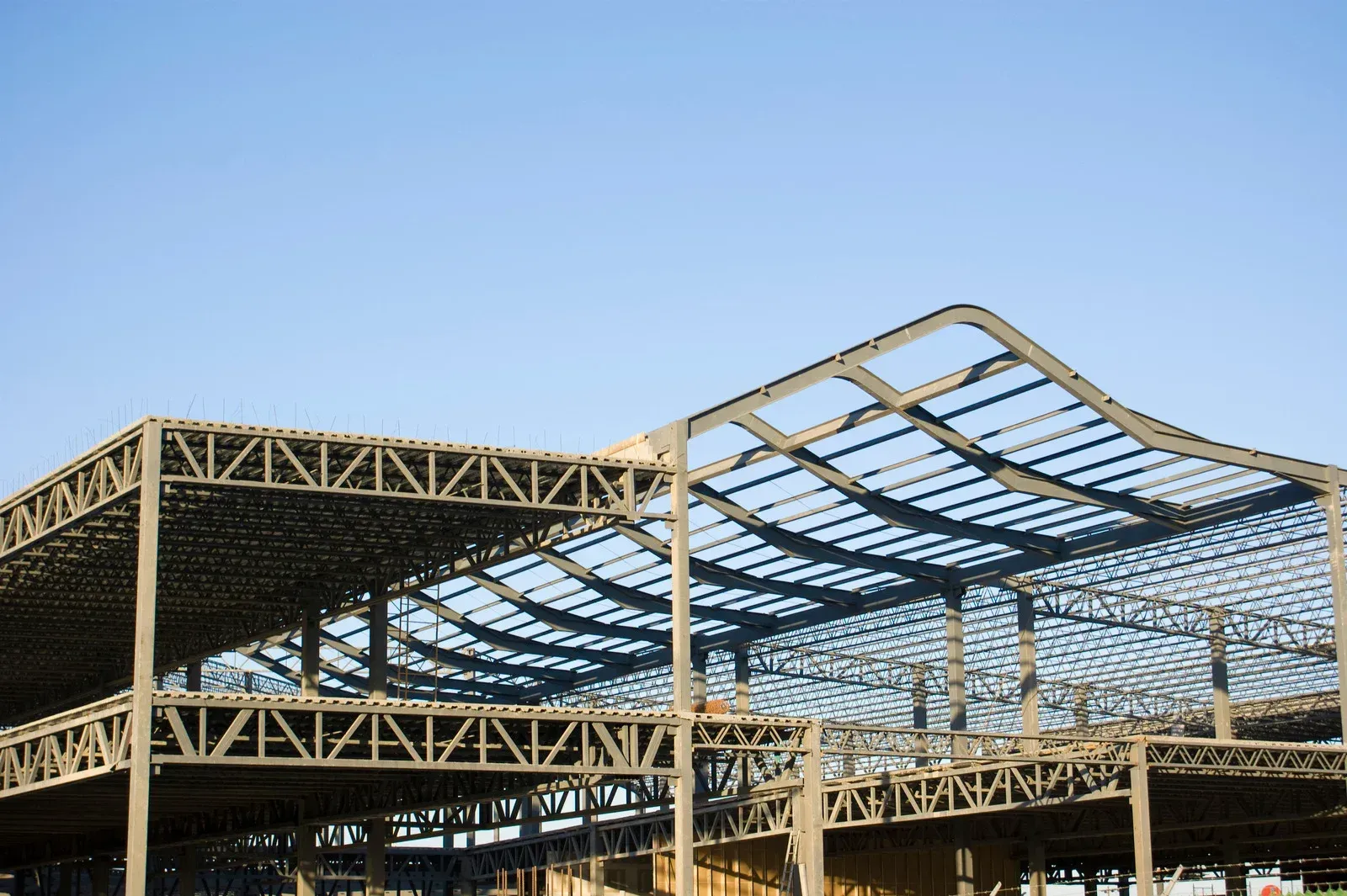 Steel structure of a building under construction, against a clear blue sky.