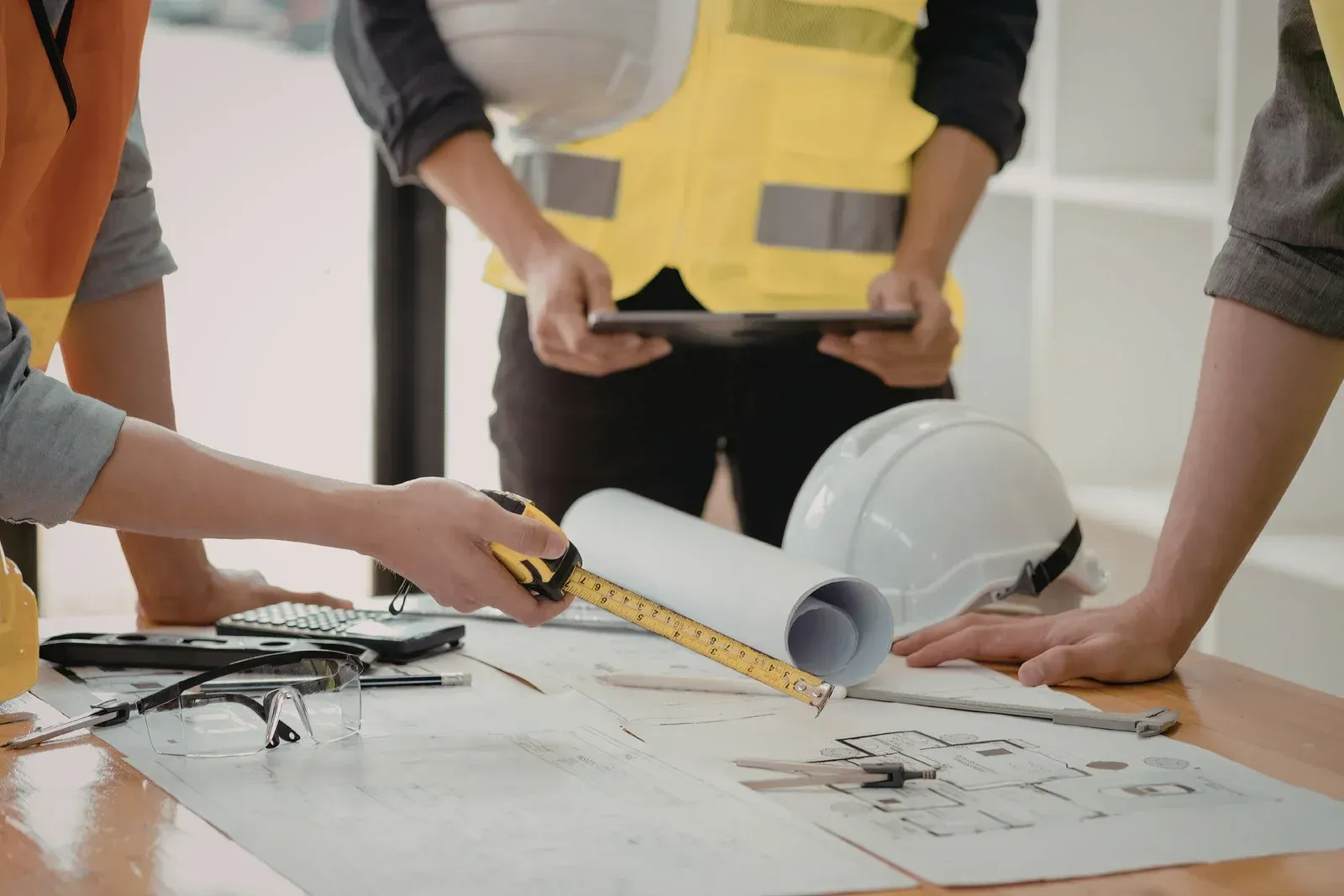 Construction workers reviewing blueprints with tools and hard hats.