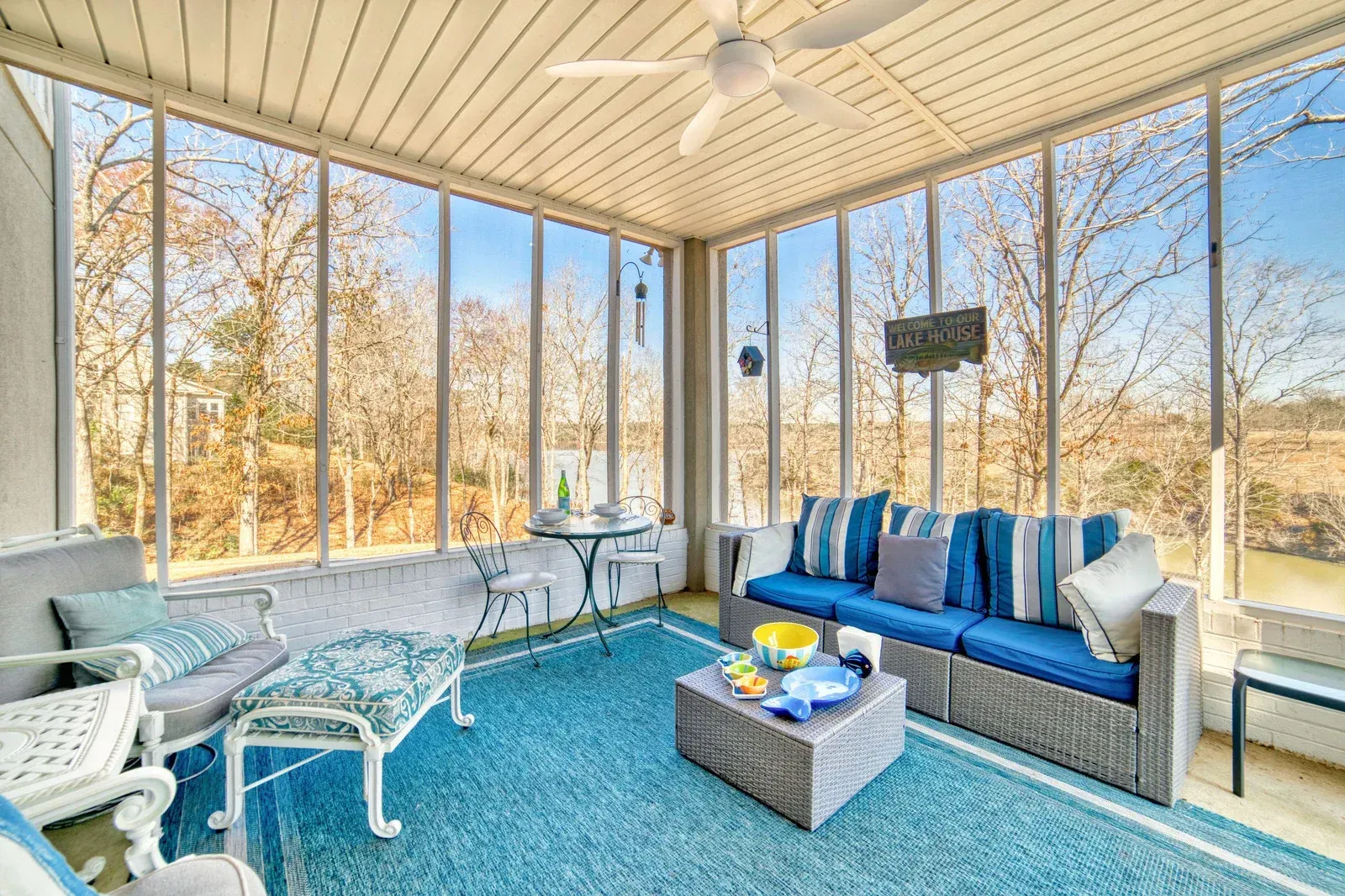 Screened porch with blue furniture, overlooking trees and water.