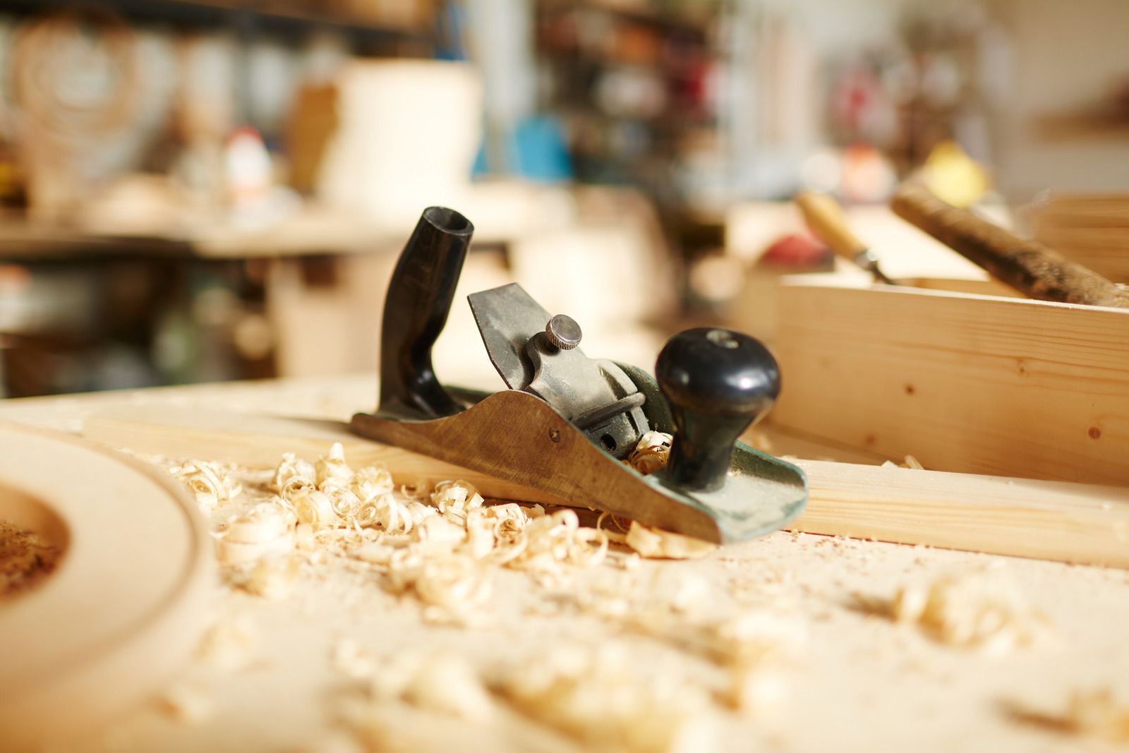 Wood plane on a wood surface with wood shavings in a workshop.