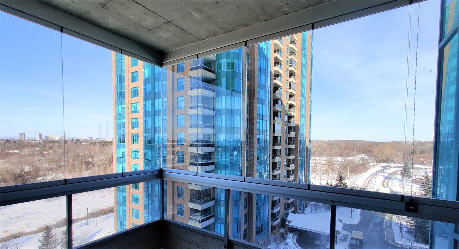View from a balcony toward a tall blue-glass high-rise building on a clear day.