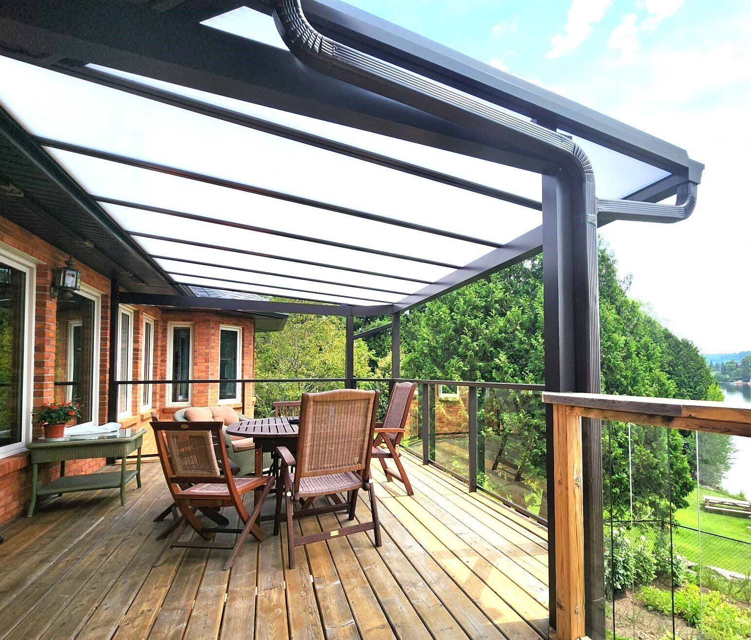 A wooden deck with a table and chairs under a canopy.