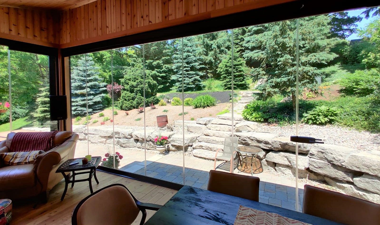 A living room with a table and chairs and a view of a forest.