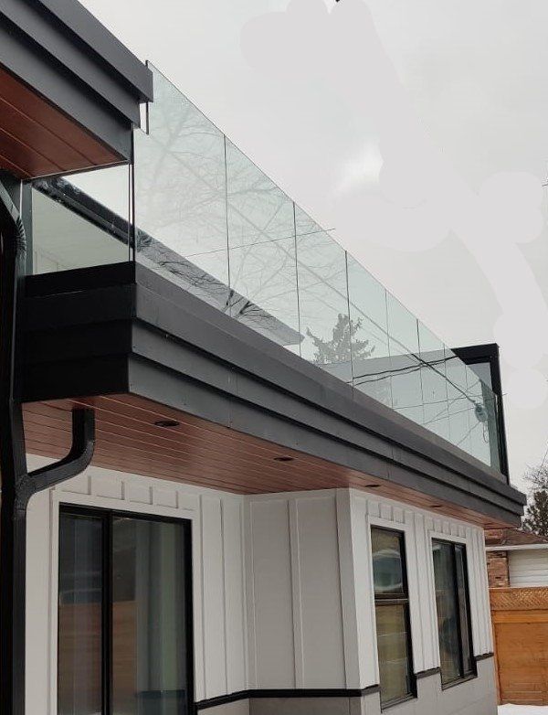 Modern house with glass balcony railing and dark trim.