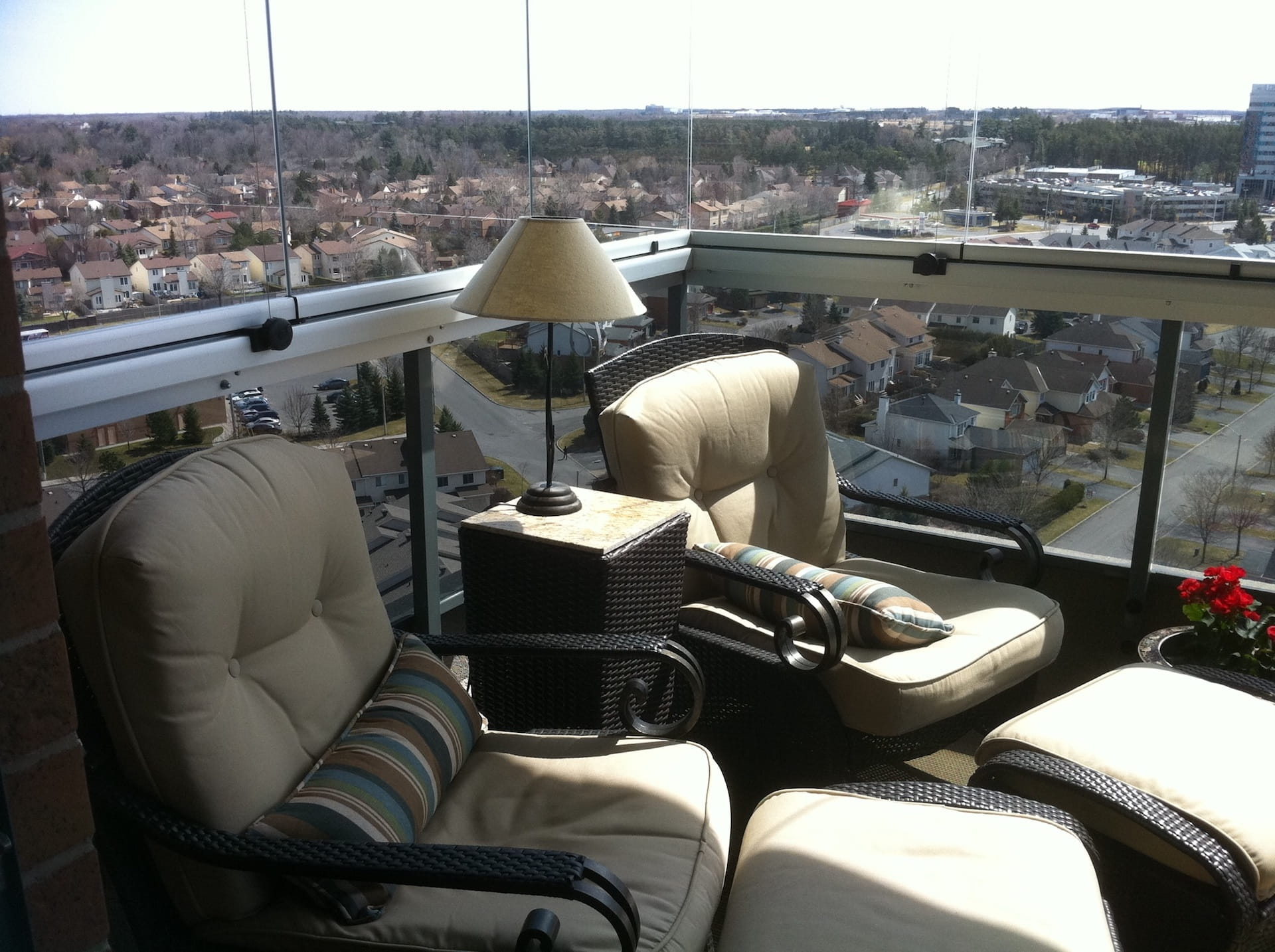 A balcony with chairs and ottomans with a view of a city